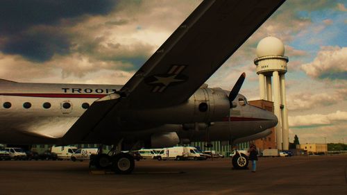 Airplane on airport runway against sky