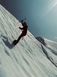 Rear view of man climbing on snow covered mountain