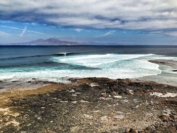 Scenic view of beach against cloudy sky