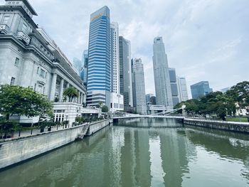 Modern buildings by river against sky in city