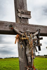 Crosses and beads hanging on wooden crucifix against sky