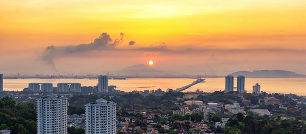 Smoke emitting from factory against sky during sunset