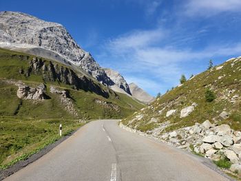 Road leading towards mountains against sky