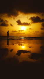 Silhouette man on beach against sky during sunset