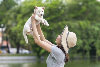 Woman playing with dog while standing outdoors