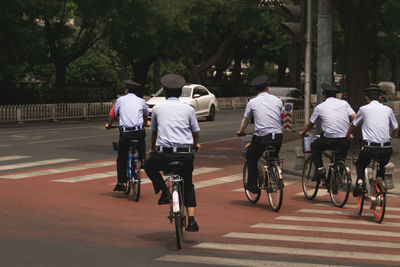 Rear view of people riding bicycle on road in city