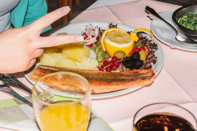 Cropped image of woman gesturing while eating food at table