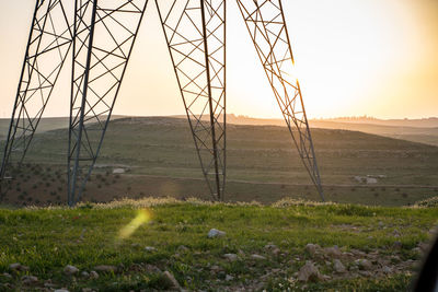 Electricity pylon on field against sky during sunset