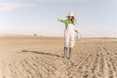 Rear view of woman standing on field against sky