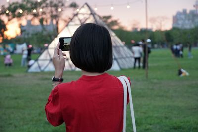 Rear view of woman photographing with smart phone