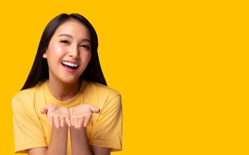 Portrait of a smiling young woman against yellow background