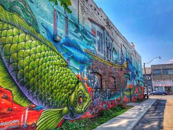 Graffiti on wall by building against sky