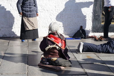 People sitting on sidewalk in city