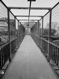Empty footpath by fence against sky