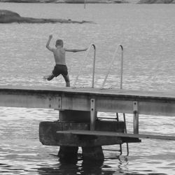 Full length of shirtless man jumping on pier