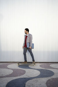 Full length of a young man standing against wall