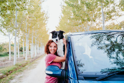 Side view of woman embracing dog through car window