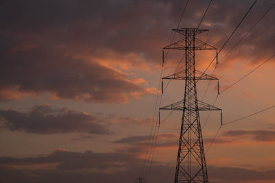 Low angle view of silhouette electricity pylon against sky during sunset