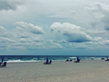 Boats in calm sea against cloudy sky