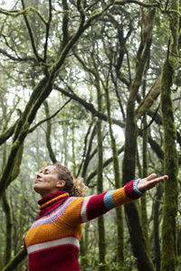 Side view of woman standing against trees