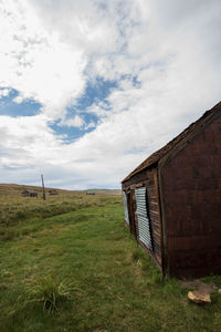 Abandoned house of ghost town on field against sky