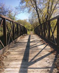 Footbridge amidst trees against sky