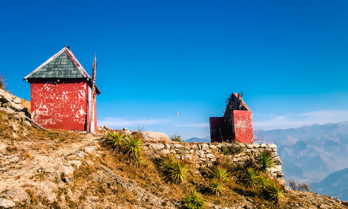 Red house amidst buildings against clear blue sky