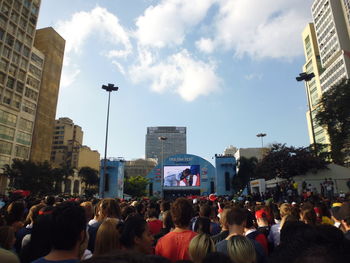 Crowd in city against sky