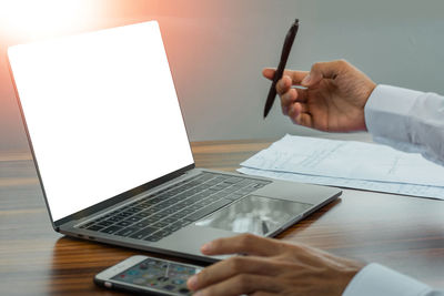 Midsection of man using mobile phone on table