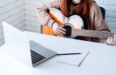 Midsection of woman using laptop on table