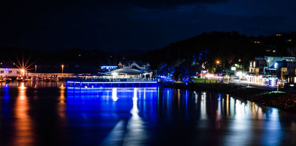 Illuminated river against sky at night