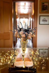 Dried flowers in vase with fairy lights and wedding shoes in historic building backlit window hall