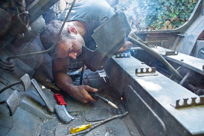 Young man welding metal in car