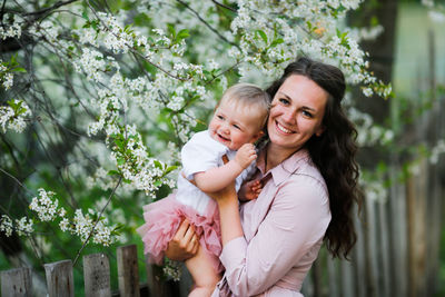 Portrait of mother with daughter embracing by cherry tree