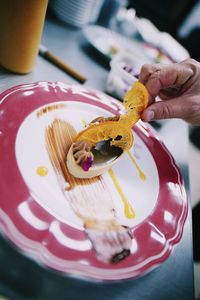 Close-up of hand garnishing dessert on table