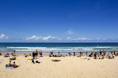 People at beach against blue sky