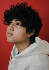 Close-up of thoughtful young man against red background