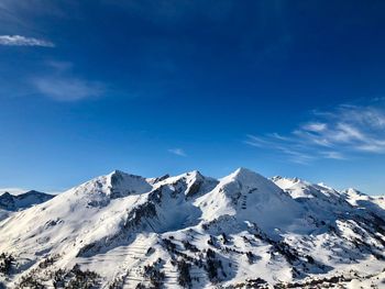 Scenic view of snowcapped mountains against blue sky