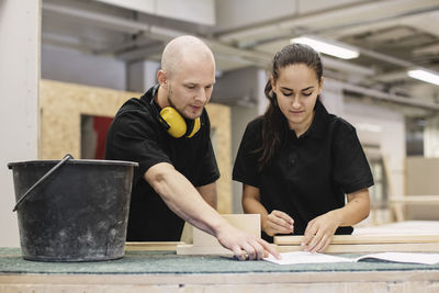 Carpentry teacher explaining female student at workbench