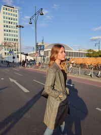 Young woman on road against sky in city