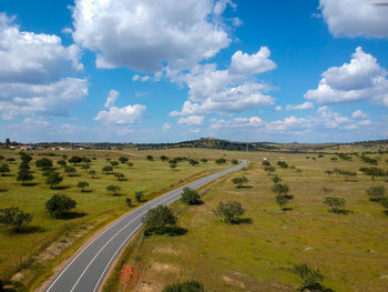 Scenic view of road amidst field against sky