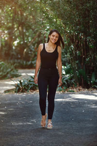 Young latina woman dressed in black jeans and tank top walking in a park in costa rica