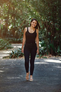 Portrait of young woman standing against trees