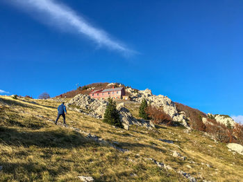 Rear view of man hiking on mountain against clear blue sky