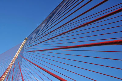 Low angle view of suspension bridge against clear blue sky