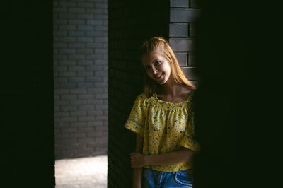 Portrait of young woman standing against wall