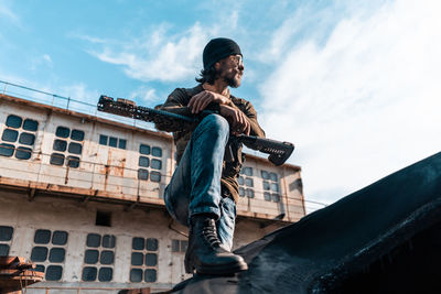 Low angle view of young man sitting against built structure