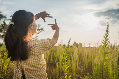 Side view of woman standing on field against sky