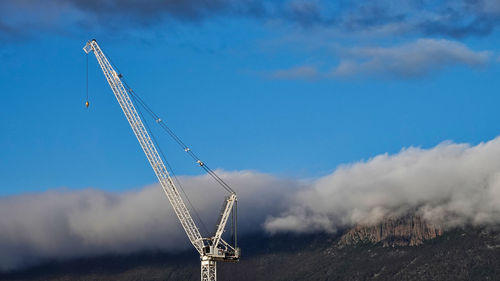 Cranes at construction site against sky