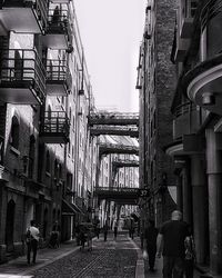 People walking on sidewalk in city against sky